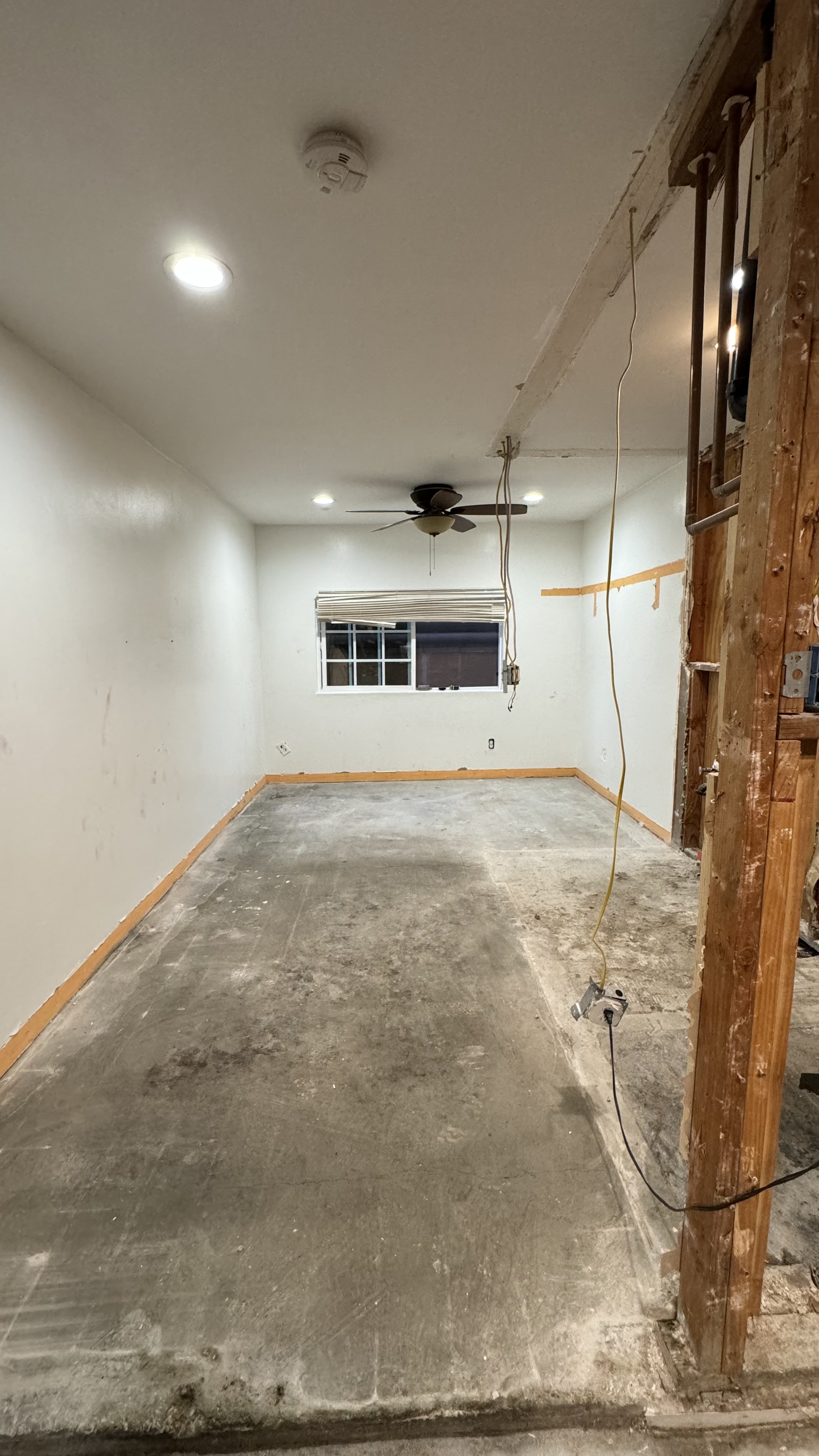Garage conversion living space with drywall, recessed lighting, and ceiling fan