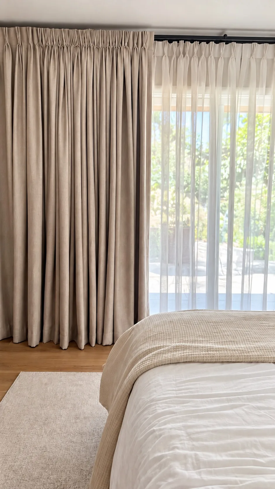 Finished ADU primary bedroom with custom-fabricated drapery and sheers over the slider