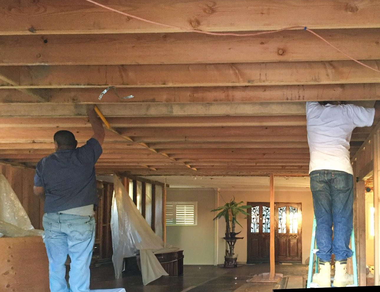 Interior ceiling joists exposed with crew working on second-story floor framing