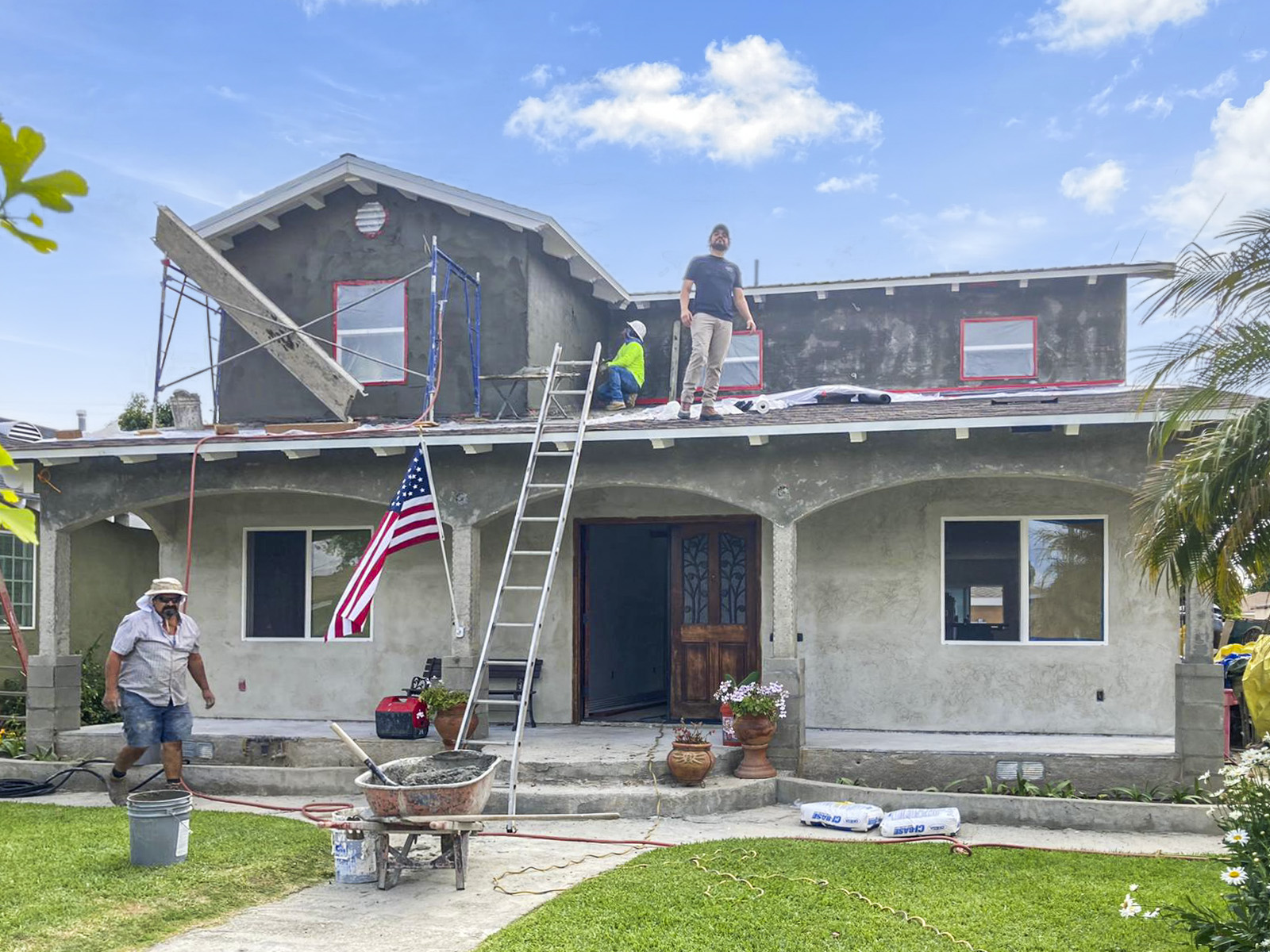 Front elevation during stucco and lath application, crew on scaffold and roof