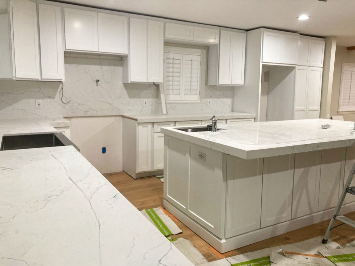Kitchen during install — cabinets set, quartz countertops being placed