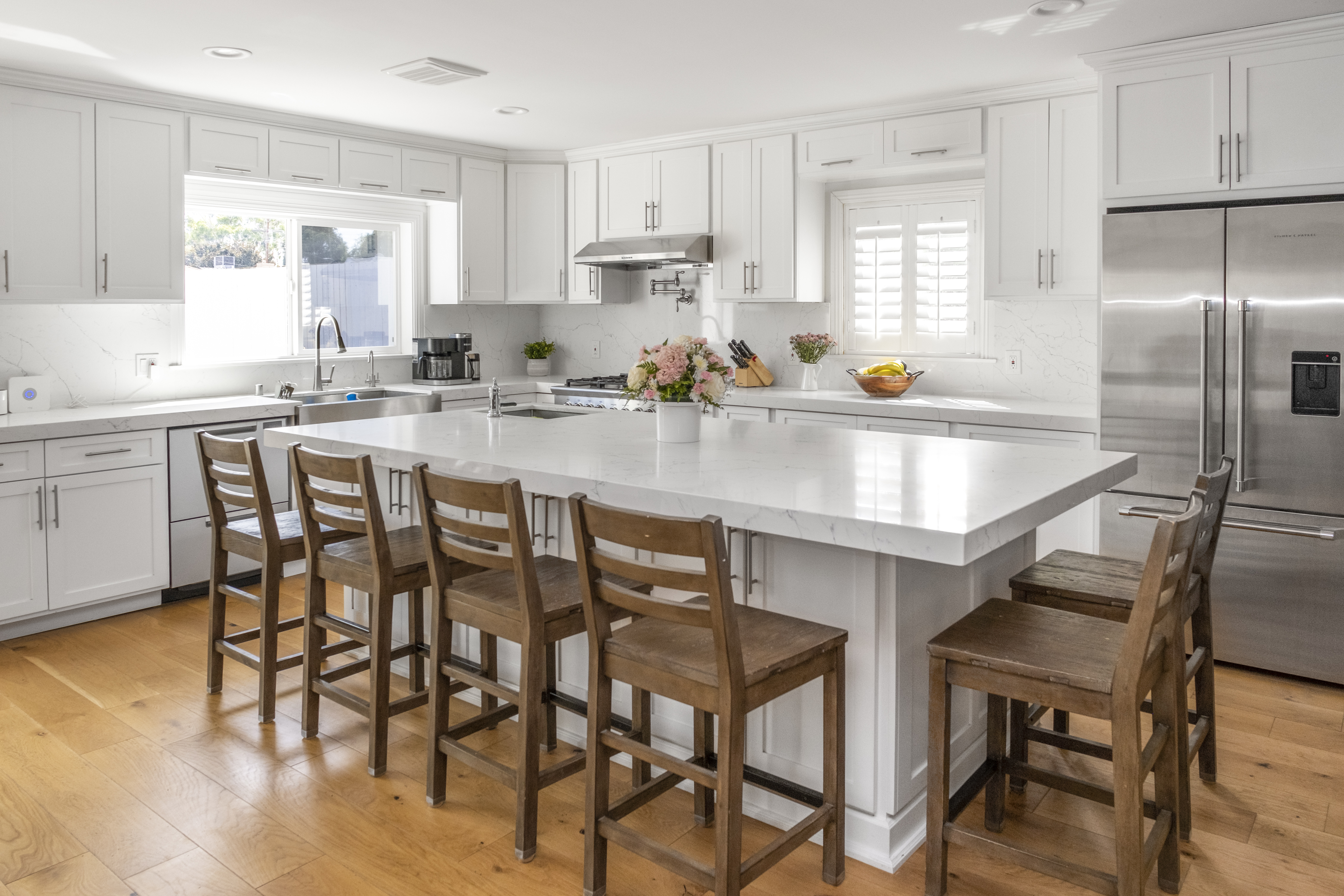 Completed kitchen with white shaker cabinets, quartz island, hardwood floors, and stainless appliances
