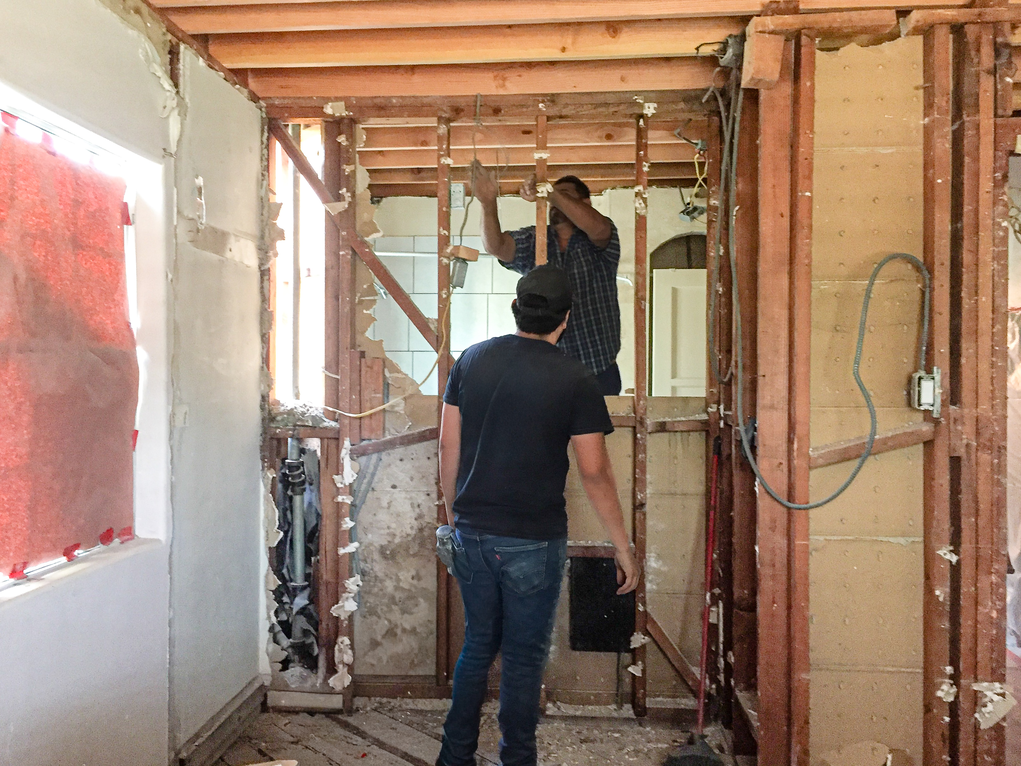 Kitchen during demolition — exposed framing, crew working, walls opened up