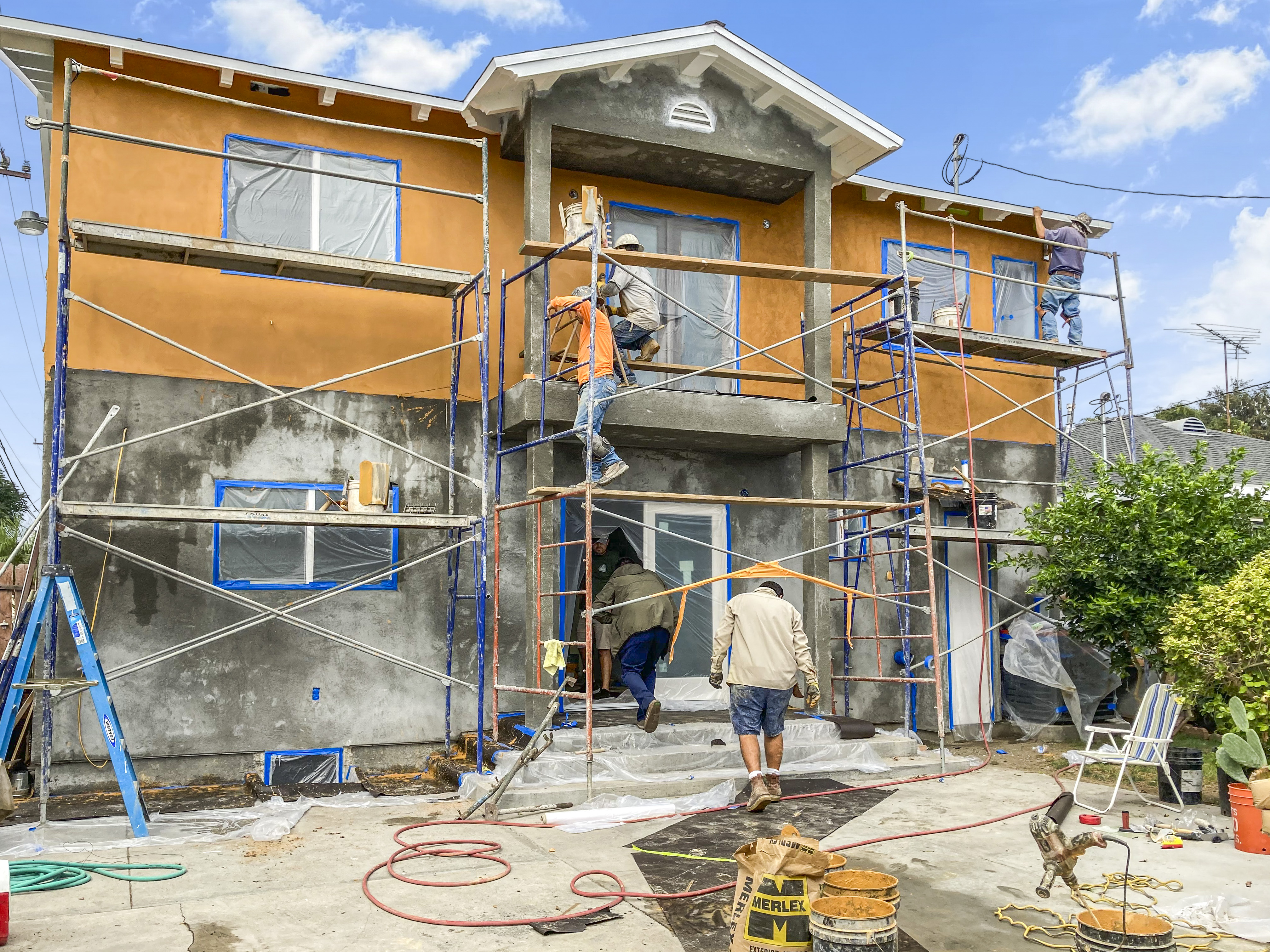 Rear elevation during stucco application, full crew on scaffolding